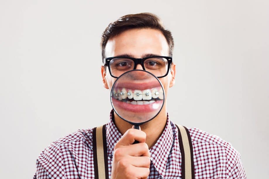 man holding magnifying glass up to braces